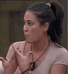 a woman in a ponytail is clapping her hands and making a face .