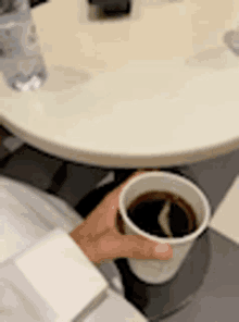 a person is holding a cup of coffee at a table .