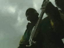 a man in a green jacket is holding a gun in his hand .