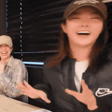 a woman wearing a nike jacket laughs while another woman looks on