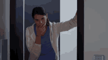 a woman covering her mouth with her hand in a doorway