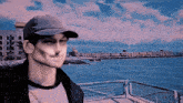 a man wearing a hat is standing on a pier overlooking the water