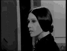 a black and white photo of a woman with long hair in a bun in a room .