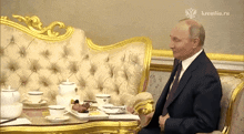 a man in a suit sits at a table with a kremlin.ru logo on the corner