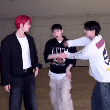 three men are standing next to each other in a room .