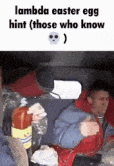 a man is sitting in the back seat of a car holding a bottle of ketchup .