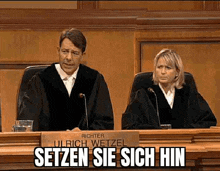 a man and a woman are sitting at a judge 's bench .
