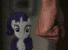 a close up of a person 's fist against a stuffed pony .
