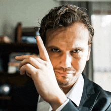 a man in a suit and white shirt is pointing his finger