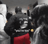 a man in a black jacket says " you 're tos " to a woman
