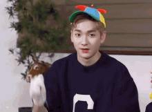 a young man wearing a sweater with the letter c on it is holding a stuffed animal
