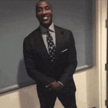 a man in a suit and tie smiles while standing in front of a window