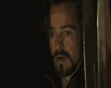 a man with a beard is looking out a window