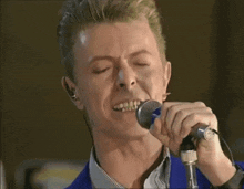 a close up of a man singing into a microphone with his eyes closed