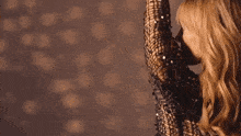 a woman in a sequined top is dancing with her arms in the air