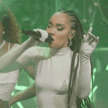 a woman with braids singing into a microphone