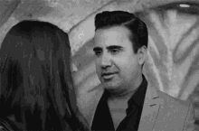 a black and white photo of a man and woman looking at each other .