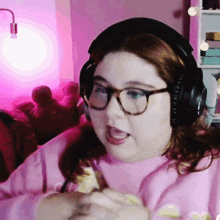 a woman wearing headphones and glasses is eating a piece of food