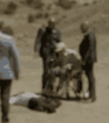 a blurry picture of a group of people standing around a person in a wheelchair .