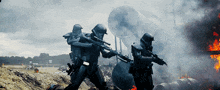 two soldiers holding guns in front of a burning building with the letter m on their helmets