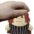 a stuffed doll with red hair is being held by a hand .