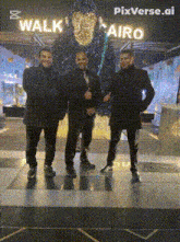 three men are posing for a picture in front of a walk in cairo sign