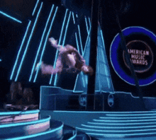 a man is flying through the air in front of an american music awards sign