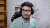 a young man wearing headphones and glasses is sitting in a chair .