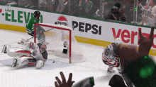 a hockey goalie makes a save in front of a pepsi banner