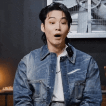 a man wearing a denim jacket and a white shirt is making a funny face .