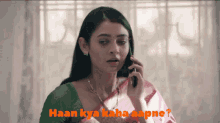 a woman in a green and pink saree is talking on a cell phone .