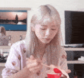 a woman with blonde hair is eating noodles with chopsticks
