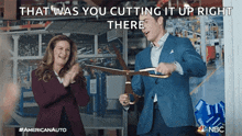 a man is cutting a ribbon with a pair of scissors while a woman applauds behind him .