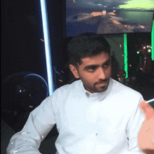 a man in a white shirt is sitting in front of a screen
