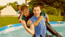 a man is carrying another man on his shoulders in a pool