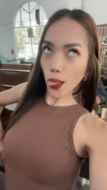 a woman in a brown tank top is making a funny face