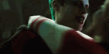 a man in a joker costume is kissing a woman in a suicide squad costume .