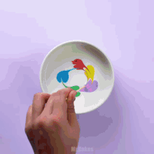 a person is mixing colors in a bowl with a toothpick