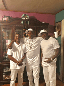 three men in white shirts pose for a photo in front of a jukebox