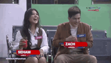 a man and a woman are sitting next to each other with their names on the screen
