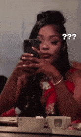 a woman is taking a picture of herself in a mirror while holding a cell phone and a cup of coffee .