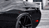 a close up of a black car with a red tail light