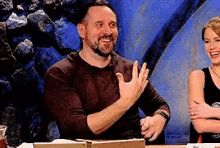 a man with a beard is smiling while sitting at a table