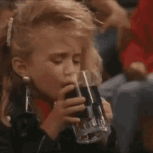 a little girl is sitting in a stadium with her hand in her mouth .