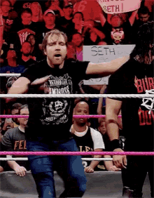 a man in a wrestling ring holds a sign that says seth