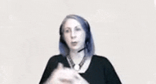 a woman wearing headphones and a microphone is making a gesture with her hand .
