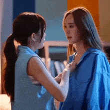 two women are standing next to each other and one of them is taking off her shirt