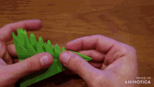 a person is holding a piece of green paper that says made in animatica on it