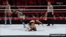 two women are wrestling in a ring while a referee looks on .