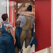 a group of people hugging in front of a red door that says " the great canadian pottery throw down "